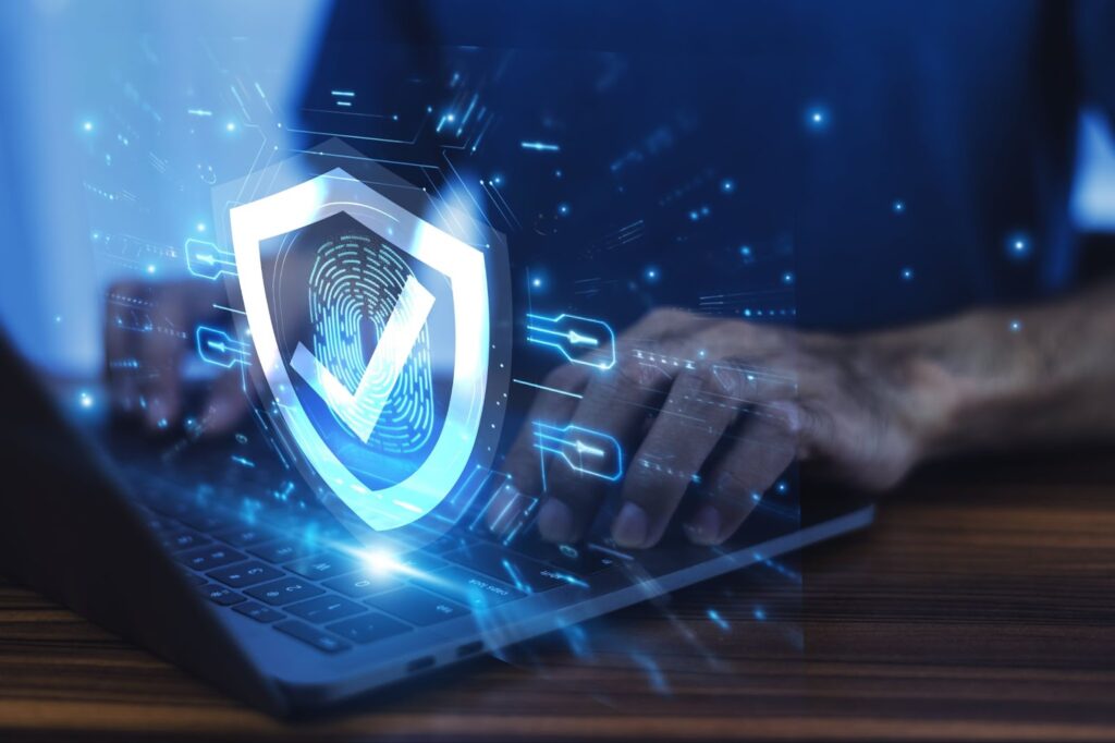 Man working on a laptop with an advanced cybersecurity shield