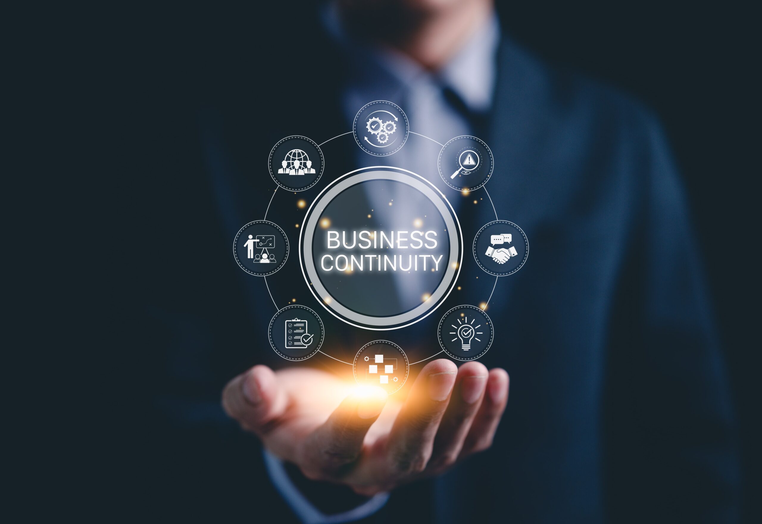 a professional individual holding up a hologram of "Business Continuity" with icons strategy, risk assessment, and operational planning