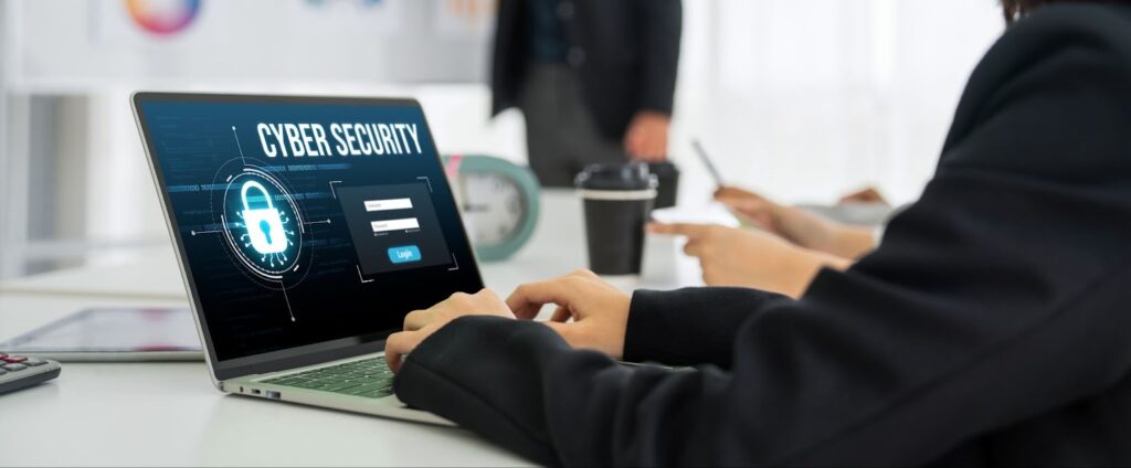 A person types on a laptop displaying a "Cyber Security" login screen.
